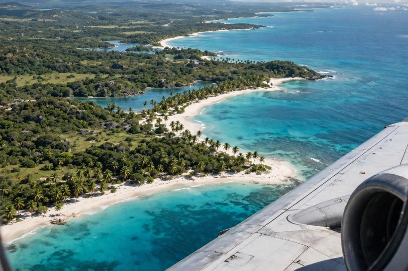 Aerial view of a tropical coastline with turquoise water, white sand and palm trees